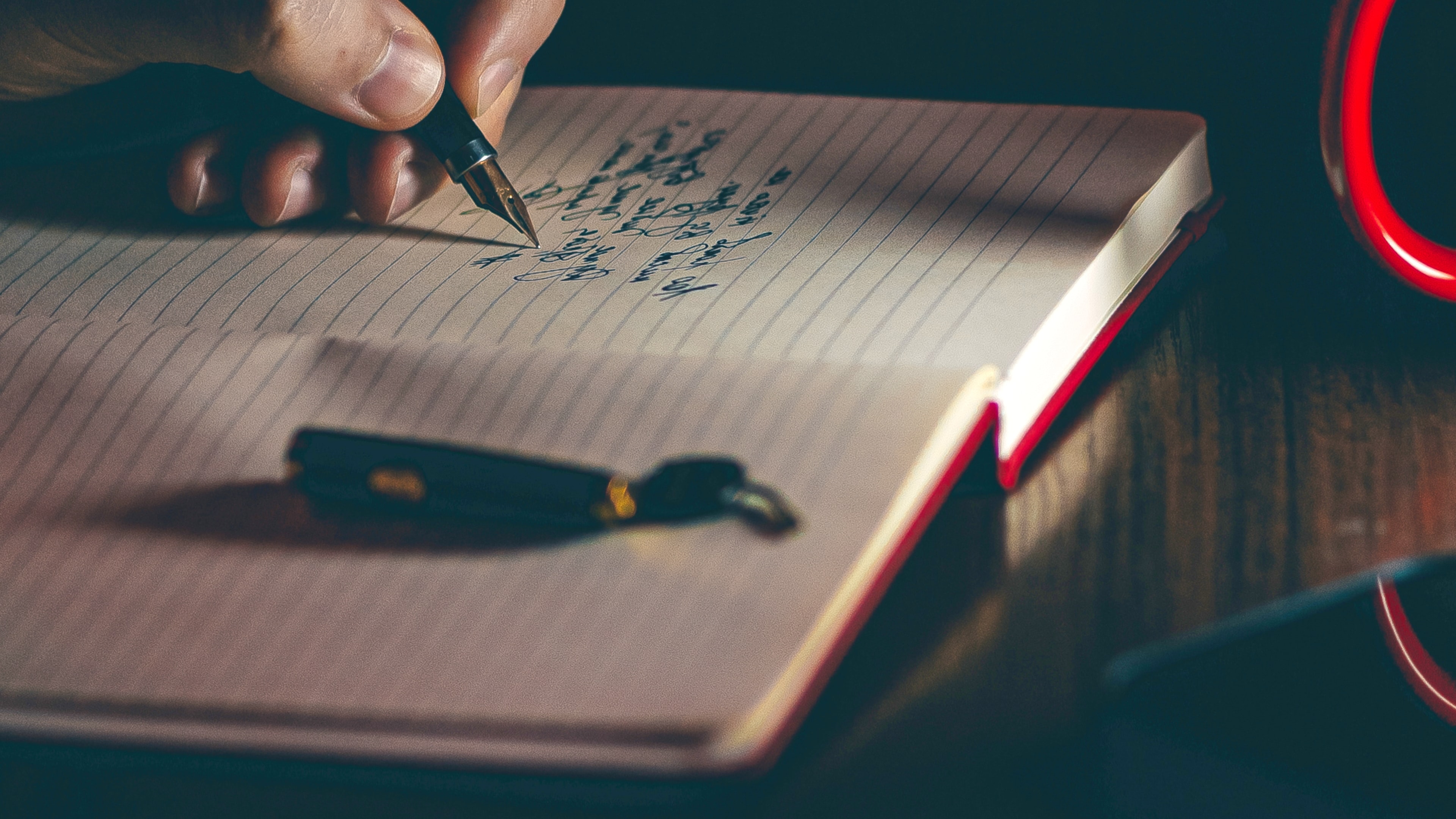 A photo of someone writing with a pen in a journal.