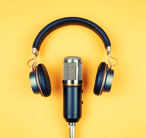 Microphone with headphones above it on yellow background