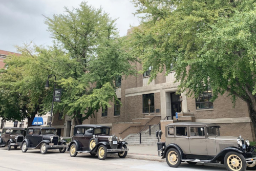 Council Bluffs City Hall with four vintage cars parked in front