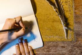 hand writing in journal with feather
