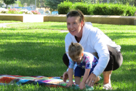 Child and adult touching the grass in the park.