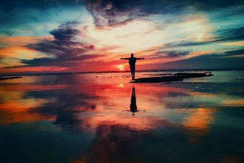 Silhouette of a person standing on a beach at sunrise