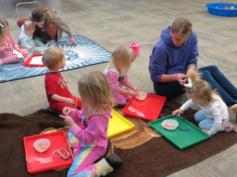 Family making fruit loop necklaces.