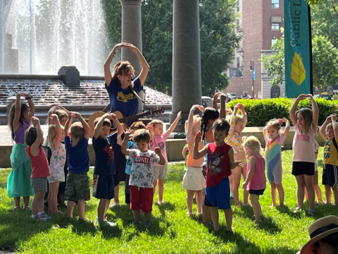 Kids dancing and singing in the park.