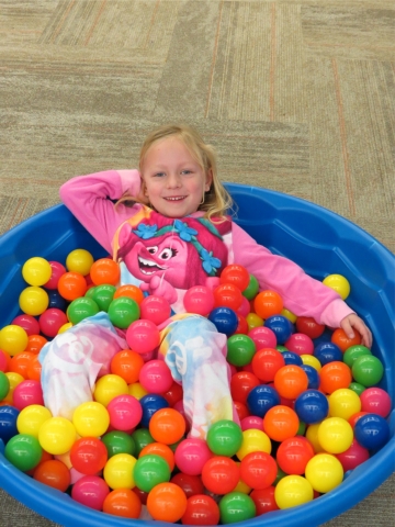 Girl in her jammies in a ball pool.
