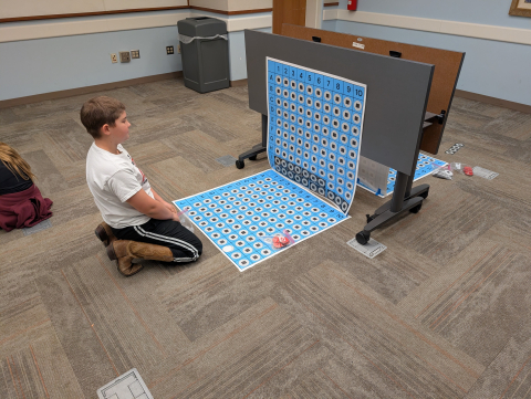 Children playing large sized battleship game.