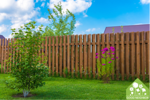 yard with fence, small tree, and purple flowers 