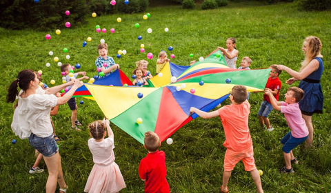 Children popping balls up on a parachute.