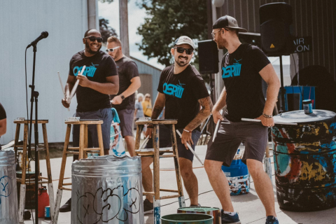 Men playing drums on a chair.