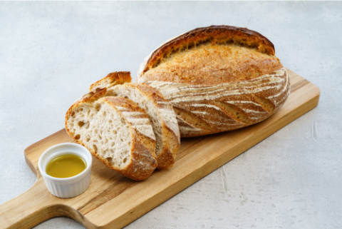 sourdough bread on wooden cutting board with melted butter in small cup