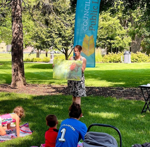 Librarian holding a book and people listening to the story.