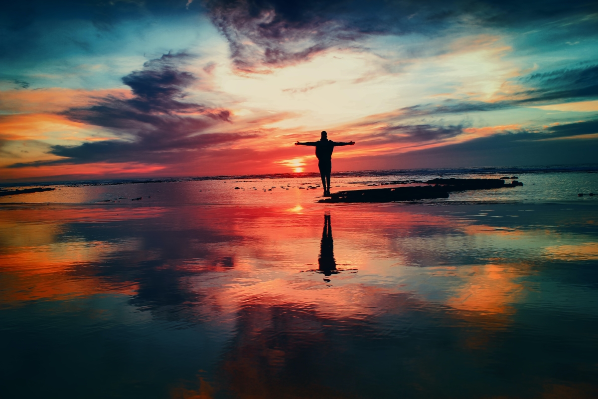 Silhouette of a person standing on a beach at sunrise