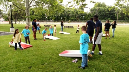 People at the park playing cornhole.