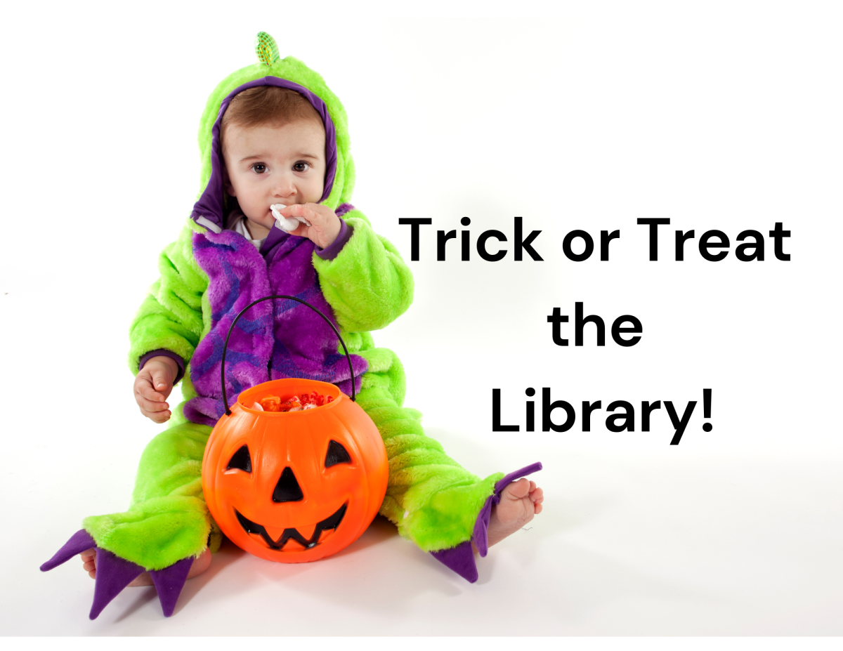 Child in dinosaur costume eating candy out of a pumpkin bucket.