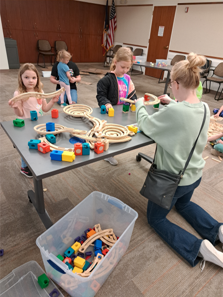 Adult and children building a marble run.