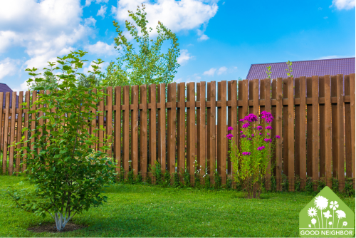 yard with fence, small tree, and purple flowers 