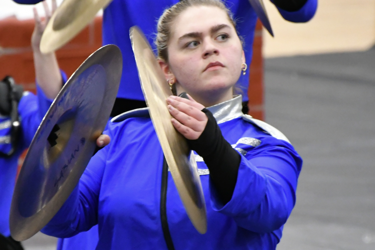 A person in a blue outfit playing the cymbals.